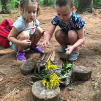 two girls build a fairy house