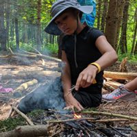 girl builds a fire in the woods