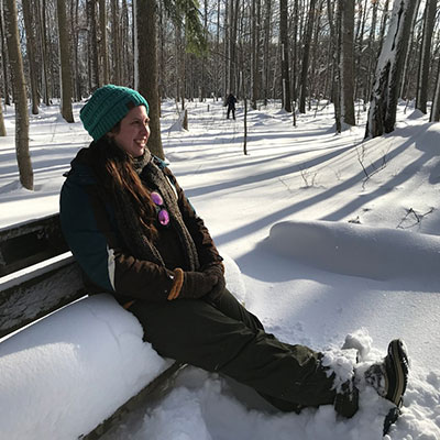 girl reposes on bench in the winter along the trails