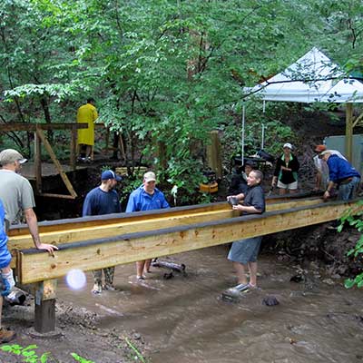 team of volunteers installs new bridge over the stream along the trail at Baltimore Woods