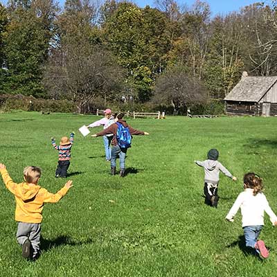 young children fly actross the field acting like migrating birds