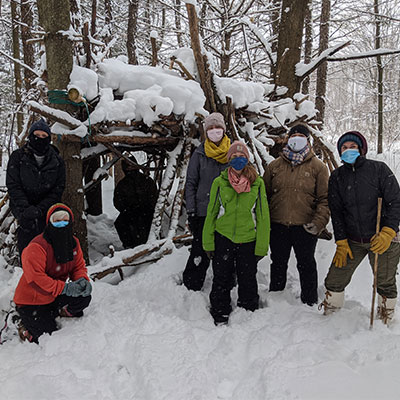 staff group photo in winter near a fort built by campers from sticks