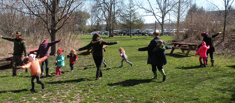 kids and parents soaring like birds outside in the filed during a spring program