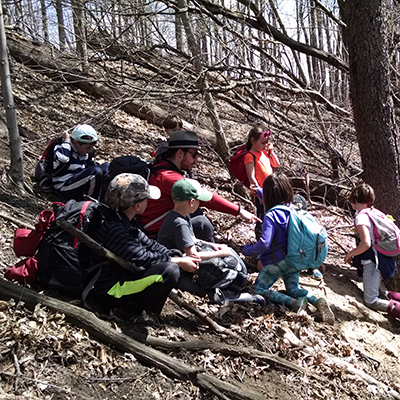 Group of Science Adventures in Nature Participants sitting among the trees at Baltimore Woods.s