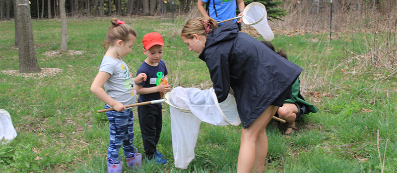kids and adults studying flying insects in nets at Earth Day