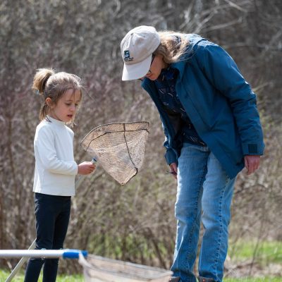 Baltimore Woods educator with a young camper holding a net.