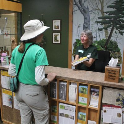 Front desk volunteer at Baltimore Woods Nature Center assisting a naturalist.