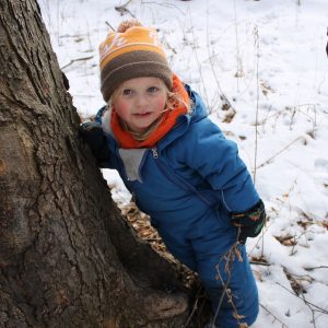 NLE participant behind a tree in the snow at Baltimore Woods.