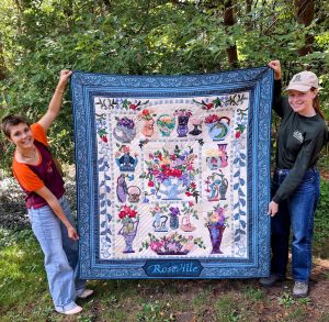 c4eabce0-8941-4f00-87fb-353881529871-1_all_30002 Baltimore Woods educators holding a quilt by Clara Pope